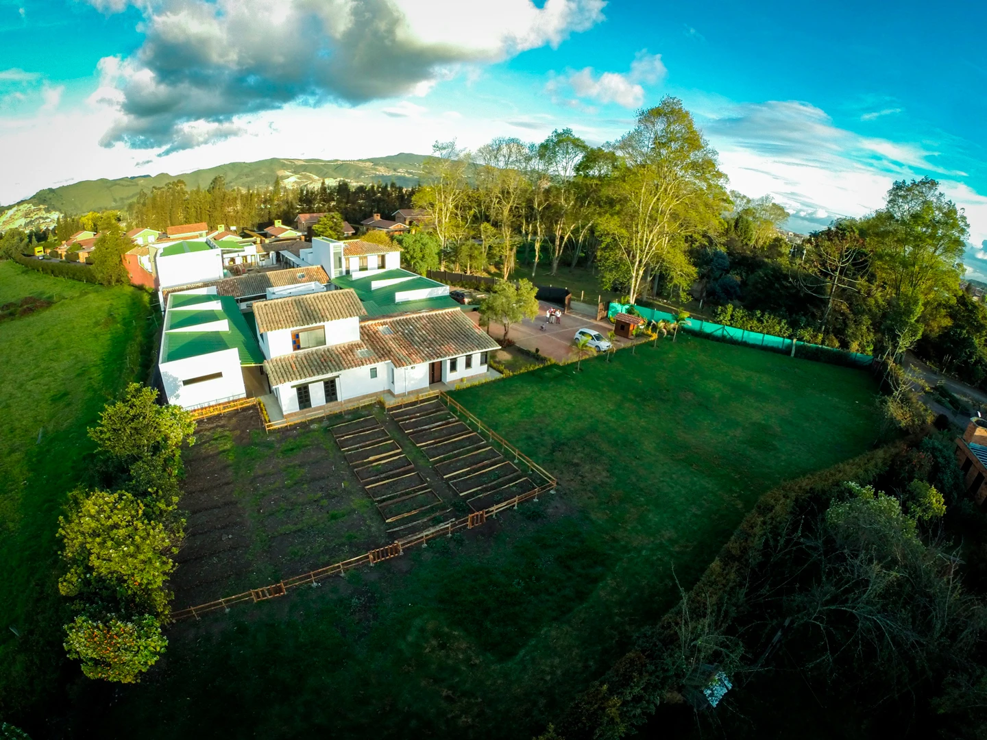 Vista con dron del colegio en Cajicá mostrando la huerta escolar y el campus rodeado de naturaleza