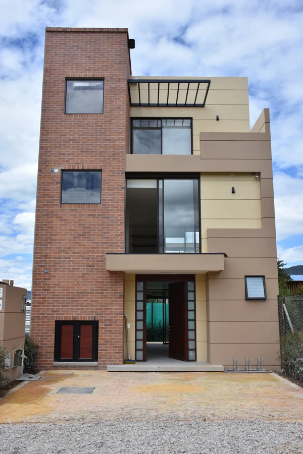 Casa tipo construida en Parcelas de Tanurín, fachada principal en ladrillo y balcones, Cajicá.